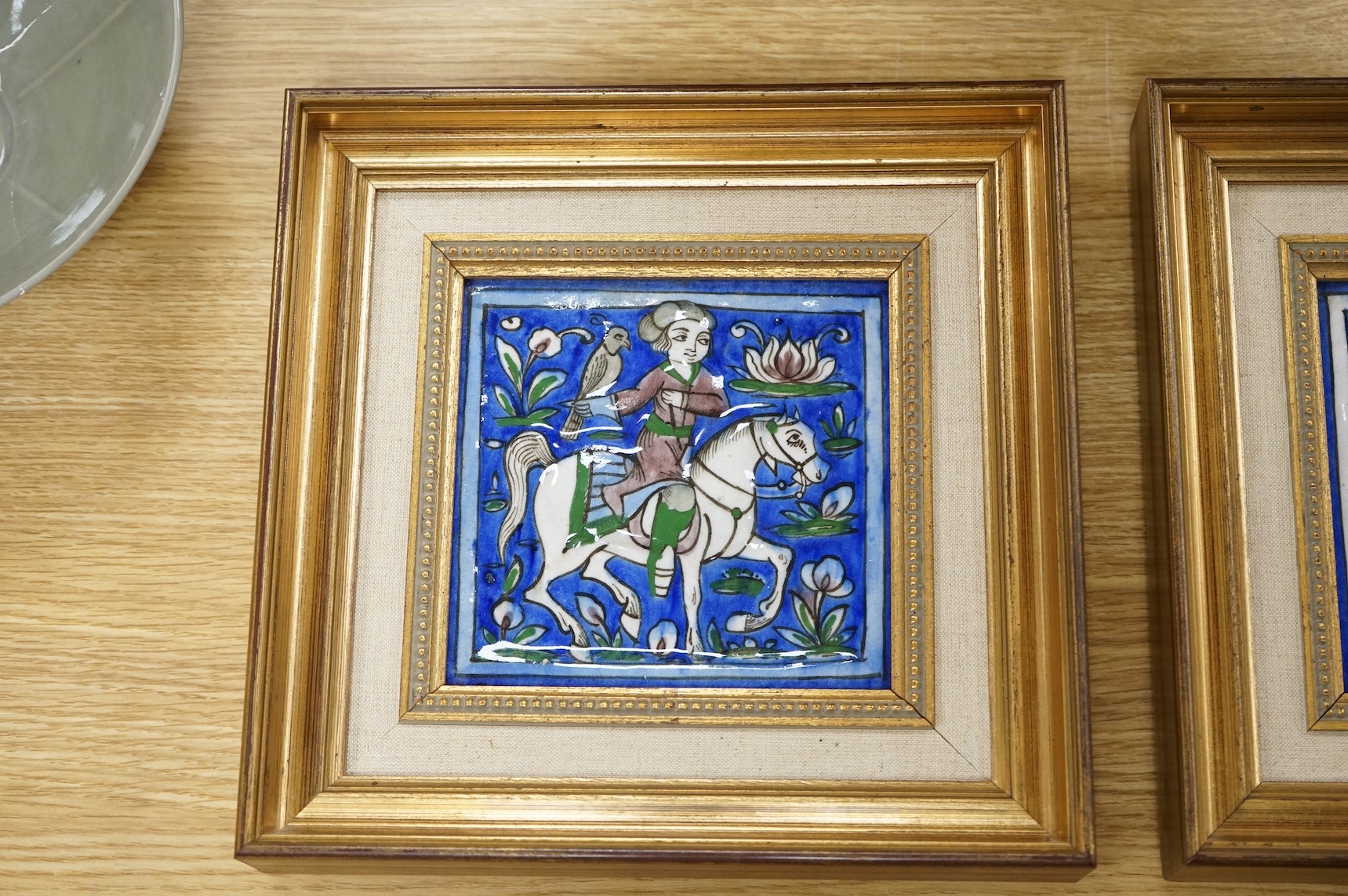 A pair of 19th century Persian fritware tiles depicting falconers, framed, 14cm squared